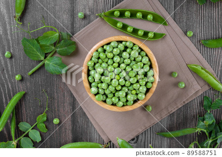Fresh organic raw green peas in a bowl with peas plants leaves on dark wooden table background, bean protein, above 89588751