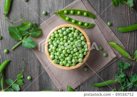 Fresh organic raw green peas in a bowl with peas plants leaves on dark wooden table background, bean protein, above 89588752