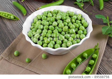 Fresh organic raw green peas in a bowl with peas plants leaves on dark wooden table background, bean protein, close up Fresh organic raw green peas in a bowl with peas plants leaves on dark wooden table background, bean protein, close up 89588756
