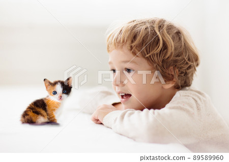 Child playing with kitten. Cat and kid at home. 89589960
