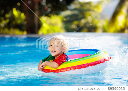 Child in swimming pool on toy ring. Kids swim. 89590013