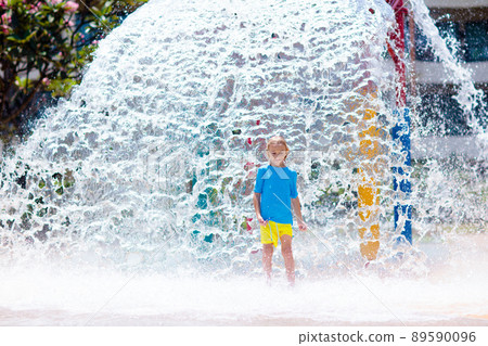Child playing under tip bucket in water park. Child playing under tip bucket in water park. 89590096