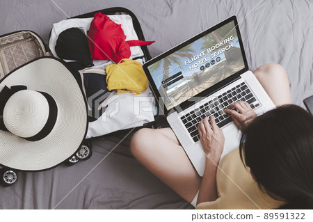 Top view Asian happy woman plan for trip by laptop booking hotel on the bed at home. Women with travel bag use notebook computer internet booking hotel. Holiday summer vacation concept 89591322