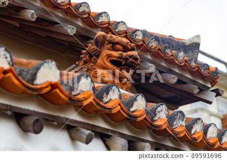Shisa watching over the town from the traditional tiled roof of Okinawa 89591696