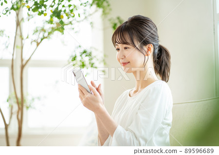 A woman who operates a smartphone, a smartphone at home 89596689