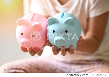 Child woman hand hold blue and pink piggy bank for saving money for education study or investment , Save money concept, daughter hands holding pink piggy bank Child woman hand hold blue and pink piggy bank for saving money for education study or investment , Save money concept, daughter hands holding pink piggy bank 89597417