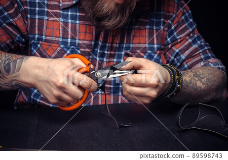 Currier of leather demonstrates leather cutting process in his leather studio Currier of leather demonstrates leather cutting process in his leather studio 89598743