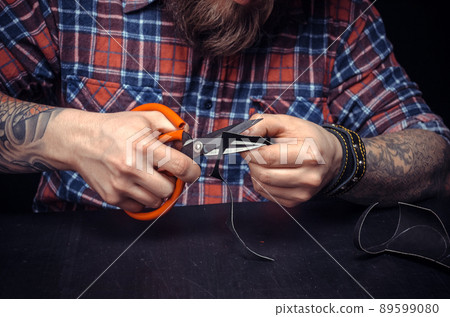 Man working with leather cutting leather outlines for his new production in his studio Man working with leather cutting leather outlines for his new production in his studio 89599080