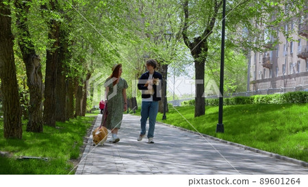 A beautiful couple walks their dogs in the park in the sunny summer. A walk in the park with pets. 89601264