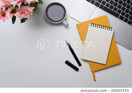 Blank notepad, coffee cup and computer laptop on white office desk. Flat lay. Blank notepad, coffee cup and computer laptop on white office desk. Flat lay. 89604393