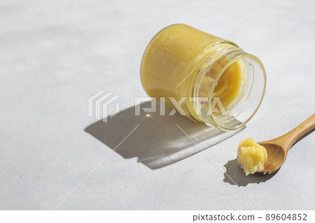 Ghee in a glass jar made with sunflower oil on a light background, copy space for text. Hard light. Ghee in a glass jar made with sunflower oil on a light background, copy space for text. Hard light. 89604852