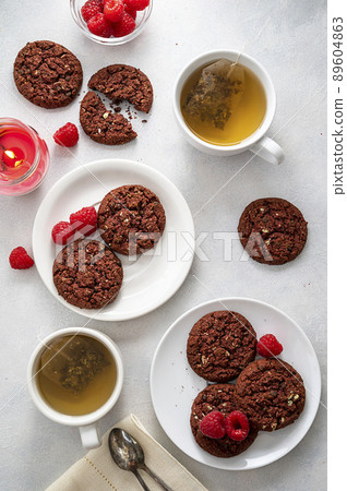 Oatmeal cookies with raspberries and herb tea cups,on bright background. Top view. Breakfast table. 89604863