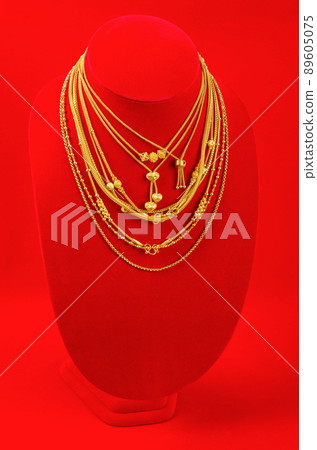 Necklace display stand with gold necklace on red Velvet fabric. 89605075