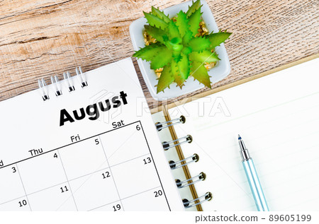 August 2022 desk calendar and open diary with pen on wooden background. August 2022 desk calendar and open diary with pen on wooden background. 89605199
