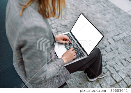 Young 30s businesswoman with laptop networking on steps of building 89605641