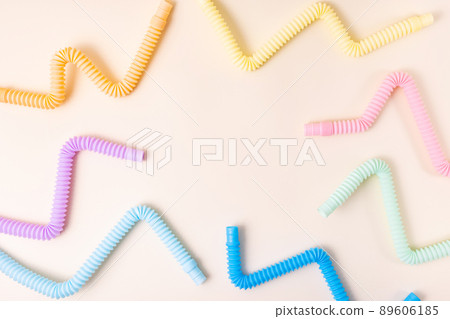 Trendy kids toys pastel colorful pop-tube on beige background. Set of forms and colors corrugated pipe and anti stressing, relaxation fidget finger toys.  89606185