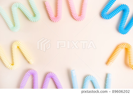 Trendy kids toys pastel colorful pop-tube on beige background. Set of forms and colors corrugated pipe and anti stressing, relaxation fidget finger toys. Trendy kids toys pastel colorful pop-tube on beige background. Set of forms and colors corrugated pipe and anti stressing, relaxation fidget finger toys. 89606202