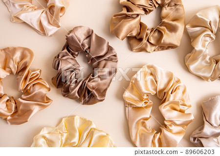 Collection of trendy silk elastic bands scrunchies on beige background. Diy accessories and hairstyles concept, luxury color Collection of trendy silk elastic bands scrunchies on beige background. Diy accessories and hairstyles concept, luxury color 89606203