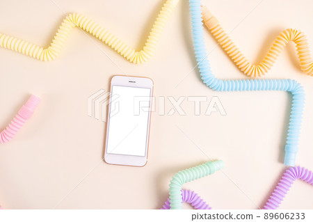 Mobile phone and Trendy kids toys pastel colorful pop-tube on beige background. Set of forms and colors corrugated pipe and anti stressing, relaxation fidget finger toys and technology . Mobile phone and Trendy kids toys pastel colorful pop-tube on beige background. Set of forms and colors corrugated pipe and anti stressing, relaxation fidget finger toys and technology . 89606233