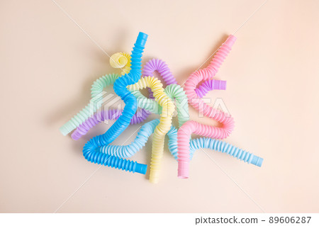 Trendy kids toys pastel colorful pop-tube on beige background. Set of forms and colors corrugated pipe and anti stressing, relaxation fidget finger toys. Trendy kids toys pastel colorful pop-tube on beige background. Set of forms and colors corrugated pipe and anti stressing, relaxation fidget finger toys. 89606287