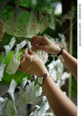 A hand of a woman tying an Omikuji A hand of a woman tying an Omikuji 89606350