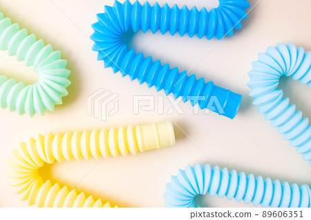 Trendy kids toys pastel colorful pop-tube on beige background. Set of forms and colors corrugated pipe and anti stressing, relaxation fidget finger toys. Trendy kids toys pastel colorful pop-tube on beige background. Set of forms and colors corrugated pipe and anti stressing, relaxation fidget finger toys. 89606351
