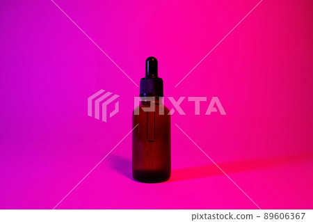 Oily serum in glass bottle with pipette on pink and purple background, neon light with copy space. Modern and futuristic cosmetic Oily serum in glass bottle with pipette on pink and purple background, neon light with copy space. Modern and futuristic cosmetic 89606367
