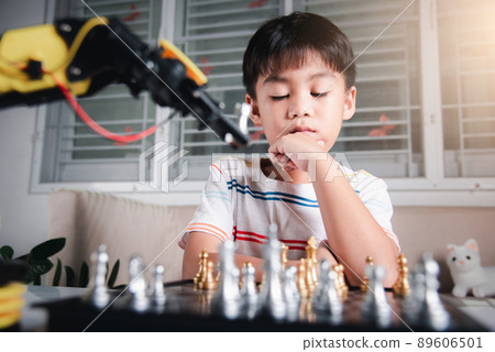 Asian little boy thinking and wait robot arm playing chess 89606501