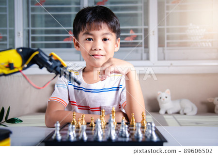 Asian little boy is playing chess with robot machine arm Asian little boy is playing chess with robot machine arm 89606502