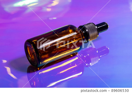 Oily serum in glass bottle with pipette on pink and purple background, neon light with copy space. Modern and futuristic cosmetic Oily serum in glass bottle with pipette on pink and purple background, neon light with copy space. Modern and futuristic cosmetic 89606530
