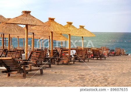 Straw umbrellas on tropical idyllic resort. Blue sea and sky with soft yellow sunlight. 89607635