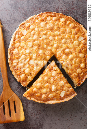 Macadamia tart nuts and creamy luxurious golden filling and baked in a buttery homemade shortcrust pastry closeup in the board. Vertical top view 89608612
