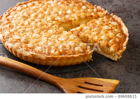 Caramel macadamia tart baked in a buttery homemade shortcrust pastry closeup in the board. Horizontal Caramel macadamia tart baked in a buttery homemade shortcrust pastry closeup in the board. Horizontal 89608615