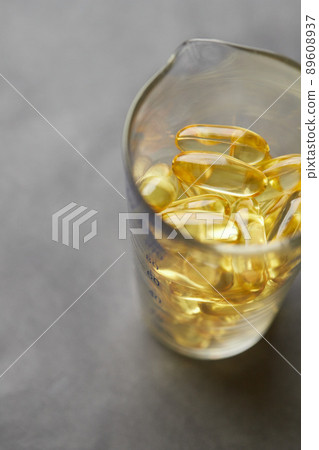 Omega-3 fatty acid capsules on a gray background in a glass. The concept of medicine and healthy living. Vertical photo. 89608937