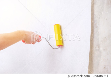 A man rolls out a canvas of white wallpaper with a A man rolls out a canvas of white wallpaper with a 89608961