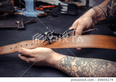 Artisan demostrating leather cutting process at his work area Artisan demostrating leather cutting process at his work area 89609274