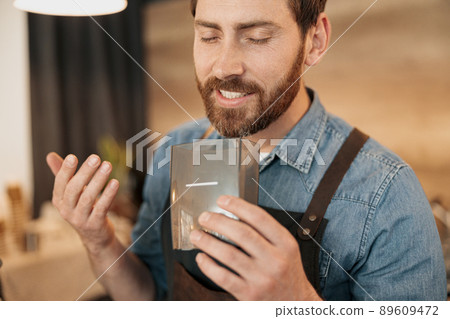 Smiling barista enjoys the aroma of coffee beans Smiling barista enjoys the aroma of coffee beans 89609472