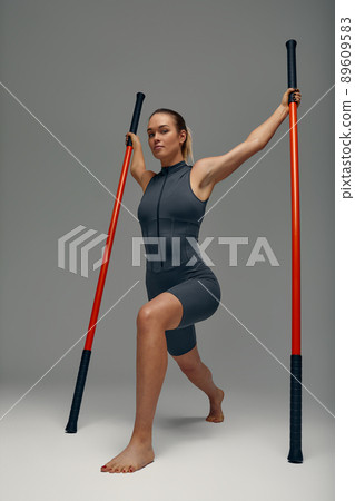 beautiful girl in sports uniform is training kung fu in the studio, fighter athlete, practicing martial arts with a stick 89609583