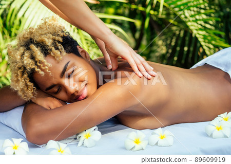 beautiful brazilian smiling girl lying on table with towel and white flowers ,massaging and pampering herself in luxury resort spa centre in Bali beautiful brazilian smiling girl lying on table with towel and white flowers ,massaging and pampering herself in luxury resort spa centre in Bali 89609919