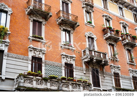 Carved balconies and stucco stone frames over the windows of the old house. Milan, Italy 89610089