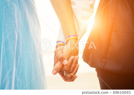 african american female groom in black suit and caucasian bride in dress in ceremony on tropical beach under wedding flover arch african american female groom in black suit and caucasian bride in dress in ceremony on tropical beach under wedding flover arch 89610093