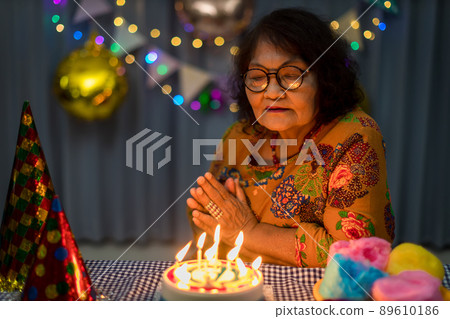 Celebrating elderly woman birthday, blowing candles on homemade baked cake Celebrating elderly woman birthday, blowing candles on homemade baked cake 89610186