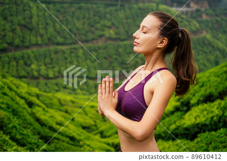 woman in violet cloth doing yoga on tea plantations in Munnar hill Kerala India woman in violet cloth doing yoga on tea plantations in Munnar hill Kerala India 89610412