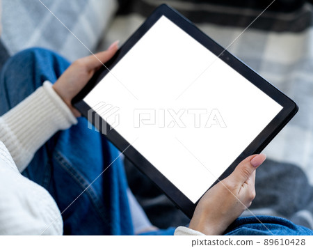 Online education. Digital technology. Mobile mockup. Unrecognizable woman holding tablet computer with blank screen in hands home interior. 89610428