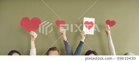 Paper red hearts of different sizes in hands of unrecognizable people on khaki background. Paper red hearts of different sizes in hands of unrecognizable people on khaki background. 89610430
