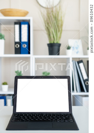 Computer technology. Digital mockup. Work place. Opened laptop with blank screen staying on office desk in light room interior. 89610432
