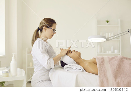 Dermatologist or beautician massaging woman's face and doing other facial treatments 89610542