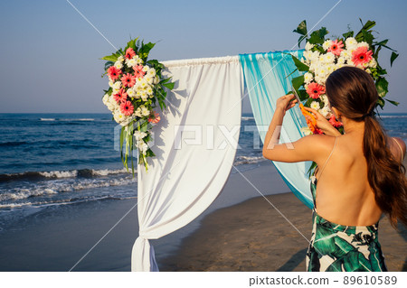 Decorator working with flowers composition for wedding arch on ocean beach 89610589