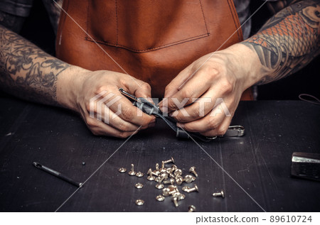 Leather workman creates quality product of leather at his place of work 89610724