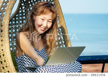 happy asian freelancer businesswoman using a laptop in summer vacation on beach tropical resort.freelance and remote work concept on sea 89611456